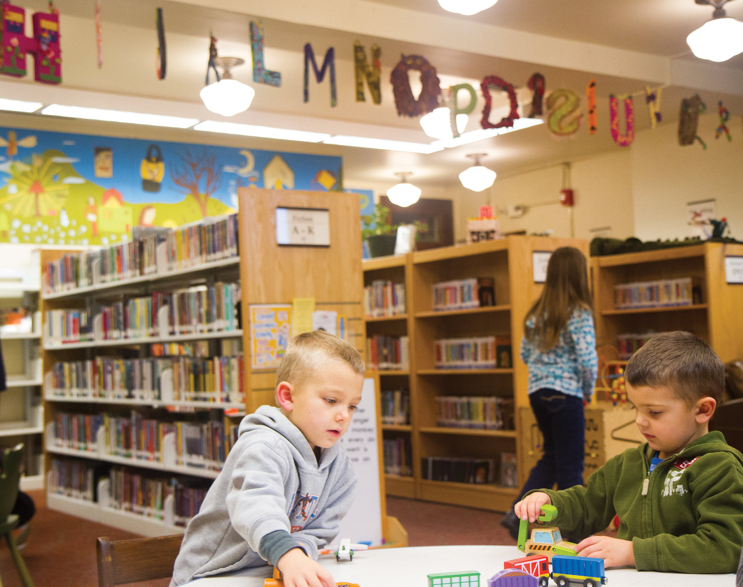 Hudson, left, and Emmett Douglas enjoy the children’s library, which is freshly decorated by the Surface Design Association, which created the 26 letters of the alphabet in fiber and paper art.